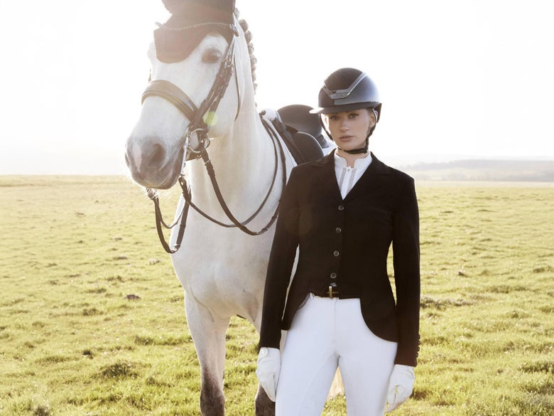 Woman standing next to her gray dressage horse wearing the LeMieux Women's Zoe Show Jacket Coat
