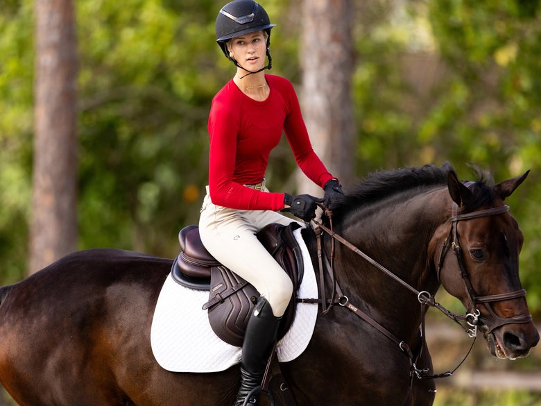 Woman riding a bay horse wearing a TKEQ sun shirt.