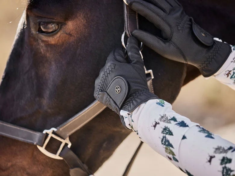 Close up of woman adjusting the leather halter on her bay horse while wearing the Kunkle Fleece Lined Winter Riding Gloves.