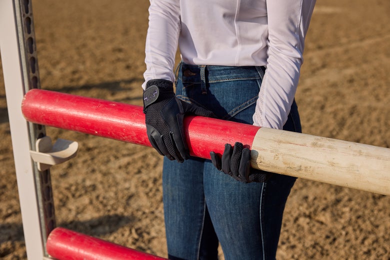 A rider adjusting a jump rail wearing Equine Couture Max Mesh Summer Riding Gloves