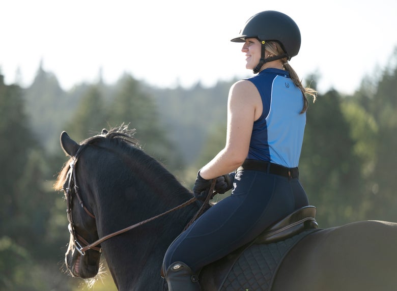 Lady riding her bay horse wearing Kerrits branded summer riding clothes