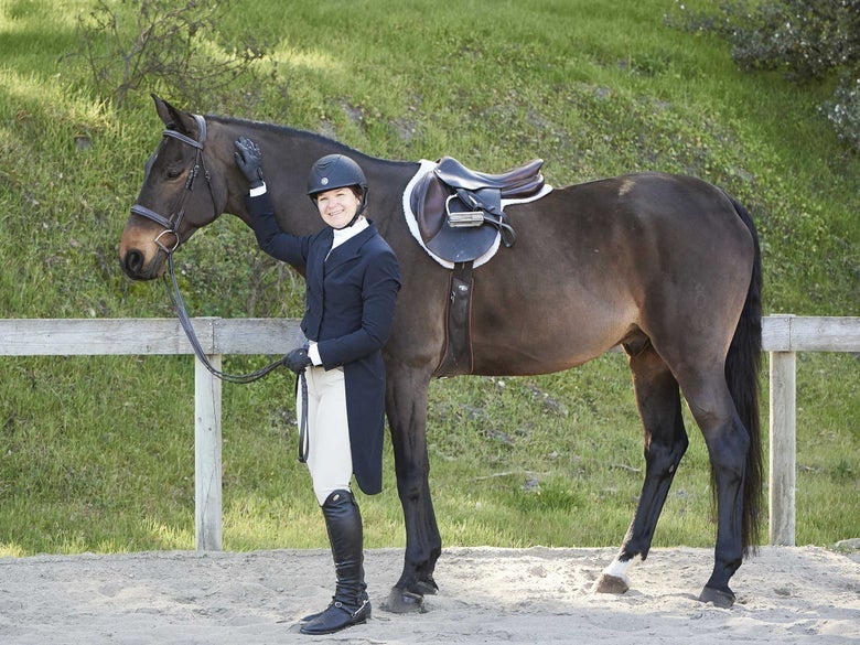 A rider and dark bay horse dressed in black hunter tack.