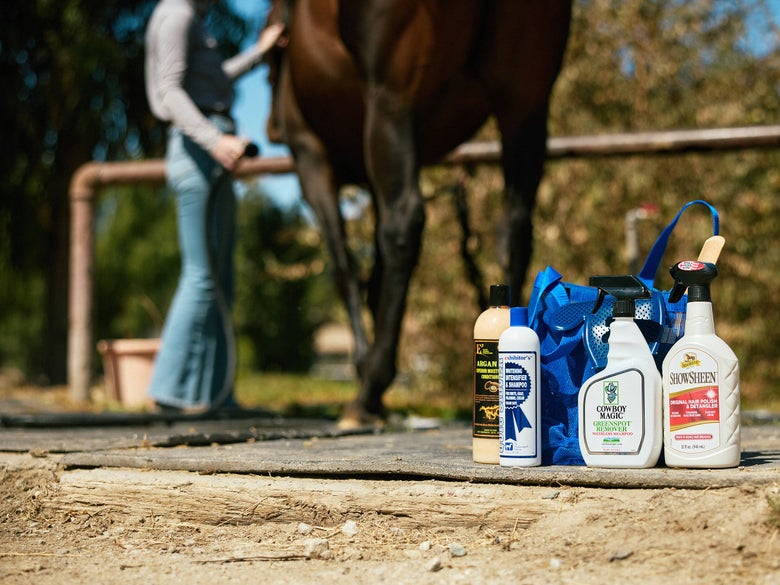 Horse bathing supplies in a wash rack, showcasing the Cowboy Magic greenspot remover spray. 