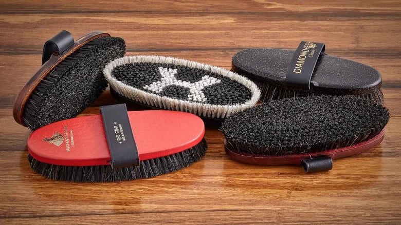 Haas brushes that are good at knocking off dirt laid out on a wood table.