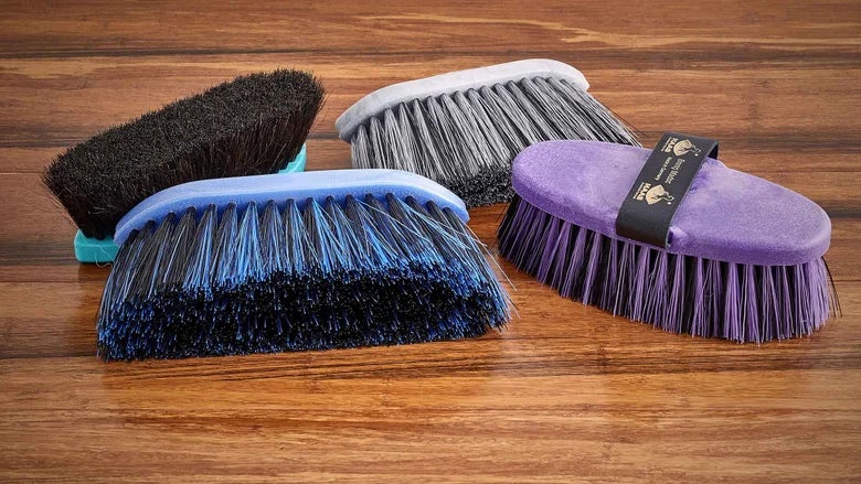 The Best Haas Brushes for Manes and Tails laid out on a wooden table.