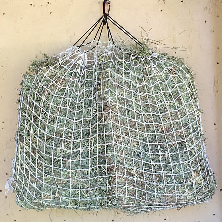 The Freedom Feeder Single Day Slow Feeder Hay Nets filled with hay.