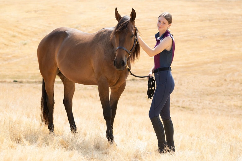 girl in a field with her beautiful bay horse