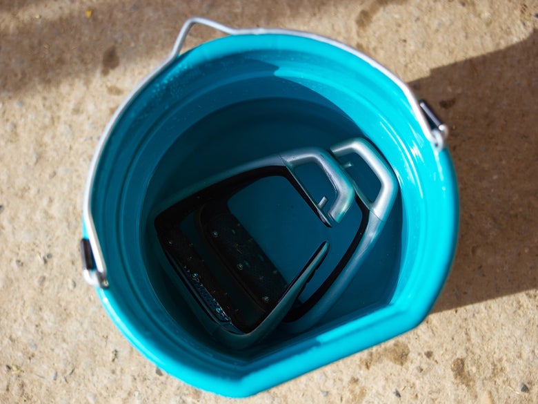 A horseback riding stirrup soaking in a bucket to clean.