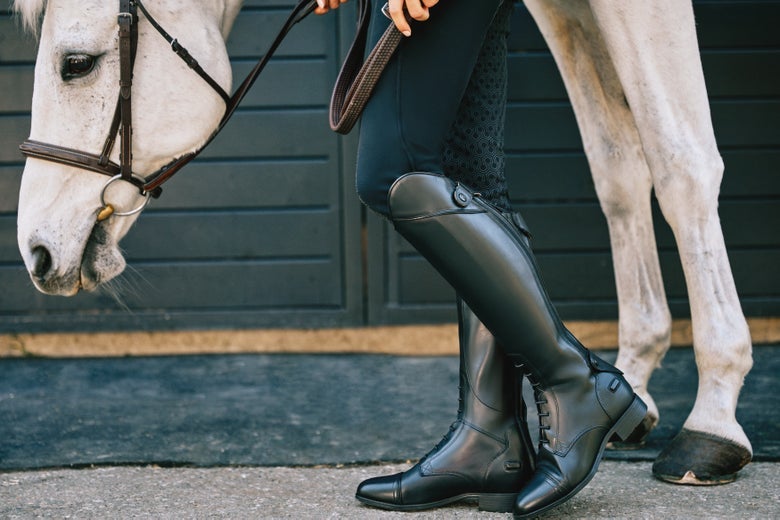 Woman in Ariat Kinsley Field boots next to a grey horse