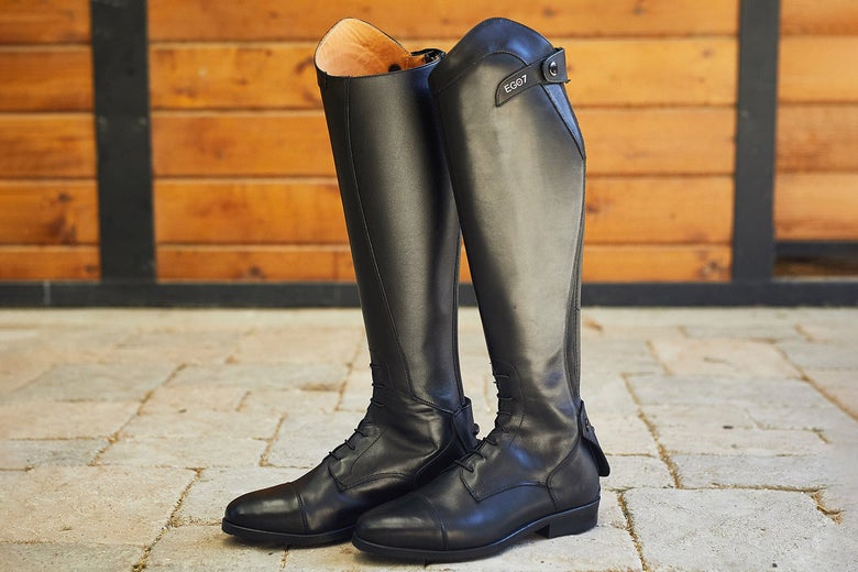 The EGO7 Orion Field Boots standing up on cement tiles with barn wood in the background.