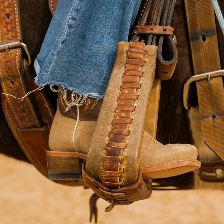 A cowgirl in the saddle, cropped in on the stirrup with her HYER Willowbrook boots on.