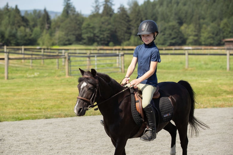 A young horseback rider on a dark bay pony wearing the Kerrits Kids Sprout Starter Tights.