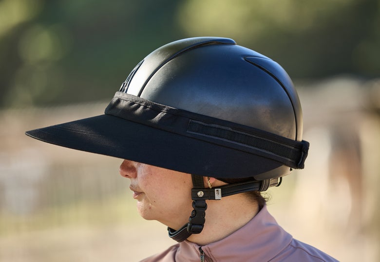 A horseback rider wearing the EquiVisor Cotton Riding Helmet Visor on her helmet.