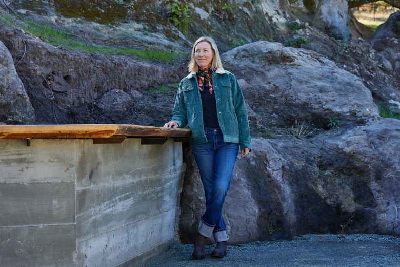 Woman standing in front of an outdoor countertop wearing the Outback Georgia Jacket Sage.