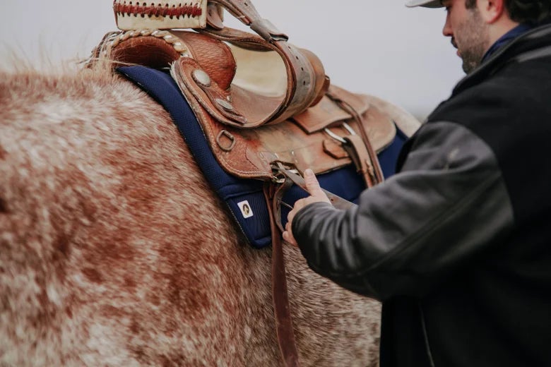  Rider cinching up their saddle and using their Ecogold Secure Western Saddle Pad 31X31