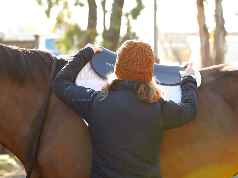a rider places a foam half pad on top of and English saddle pad