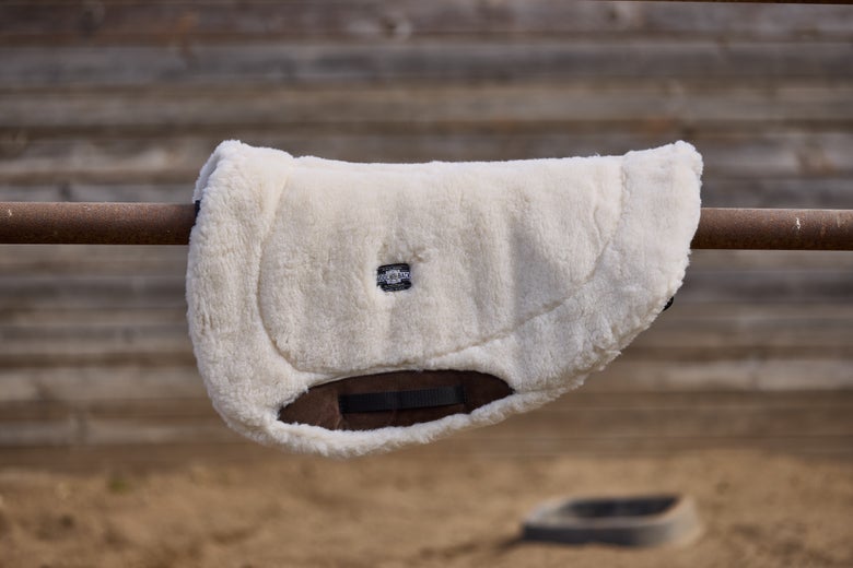 The Toklat WoolBack Round Saddle Pad Contoured sitting on a tie rail.