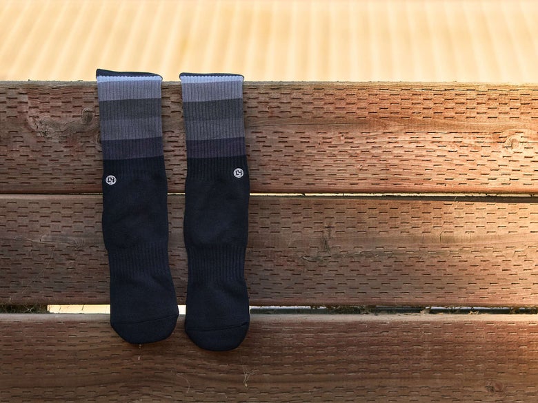 The C4 Performance Riding Socks in Black on a wooden fence.
