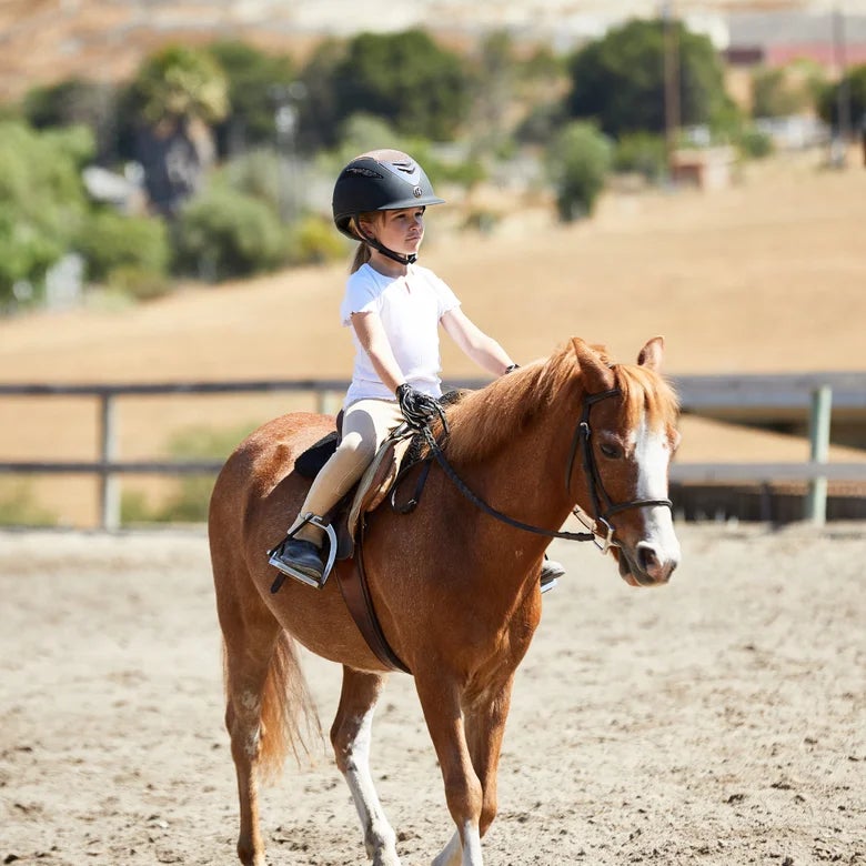 Little girl riding her pony in English tack and apparel. 