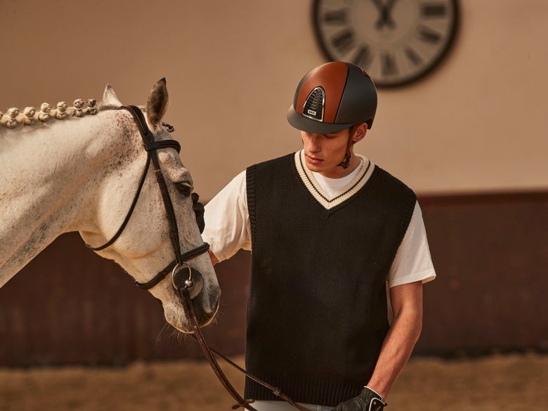 Man wearing a KEP Italia helmet standing next to a grey horse