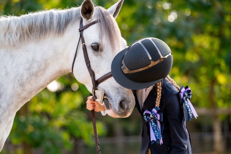 A young rider wearing a Hunter Star Lady Helmet with a grey horse.