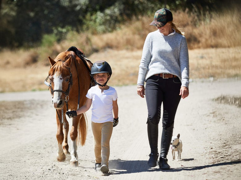 Camp instructor with her riding camp student that is leading a tacked up pony.