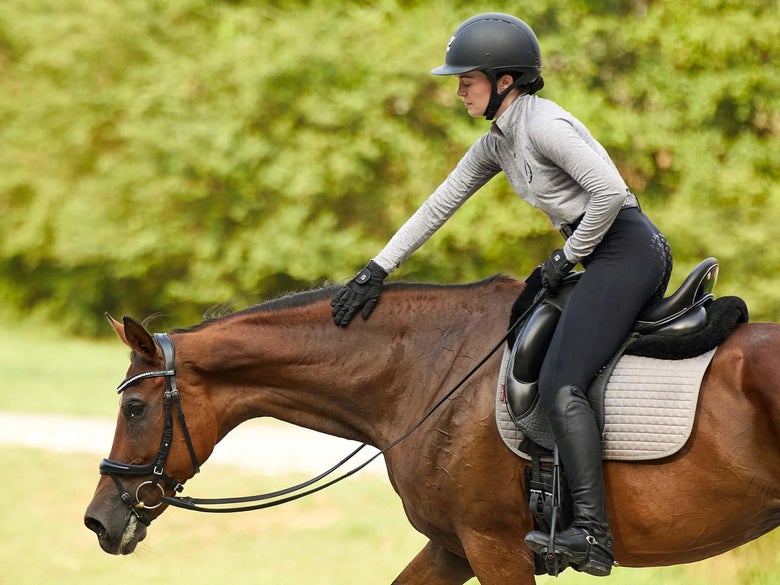 A rider patting her bay horse after their ride.
