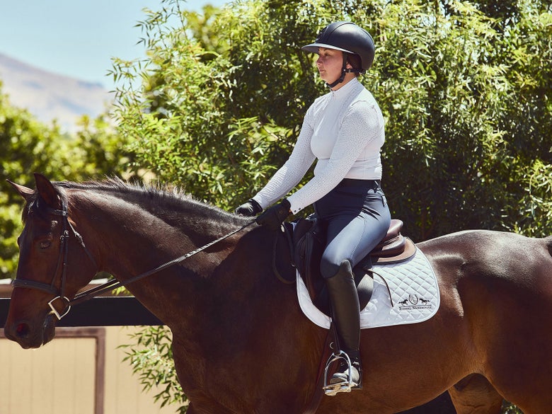 A horseback rider riding with reins in the driving position.