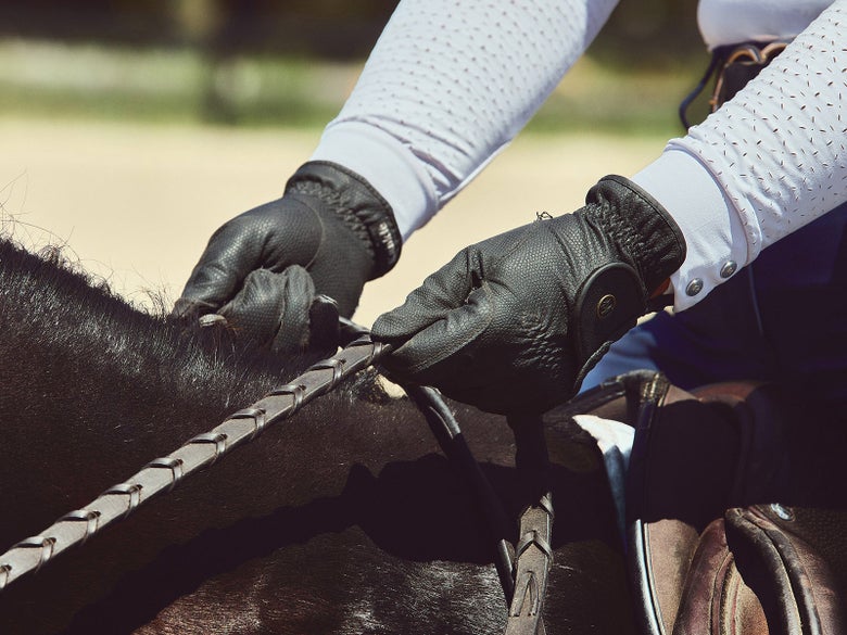A horseback rider holding her reins in the driving rein position.