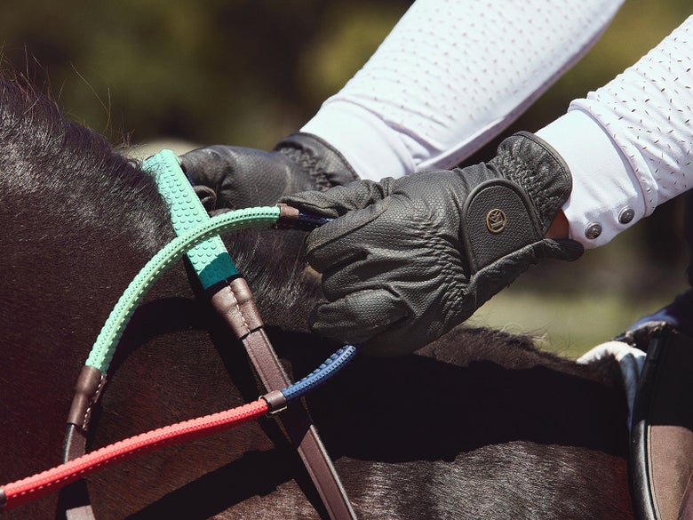 A horseback rider riding with rainbow reins.