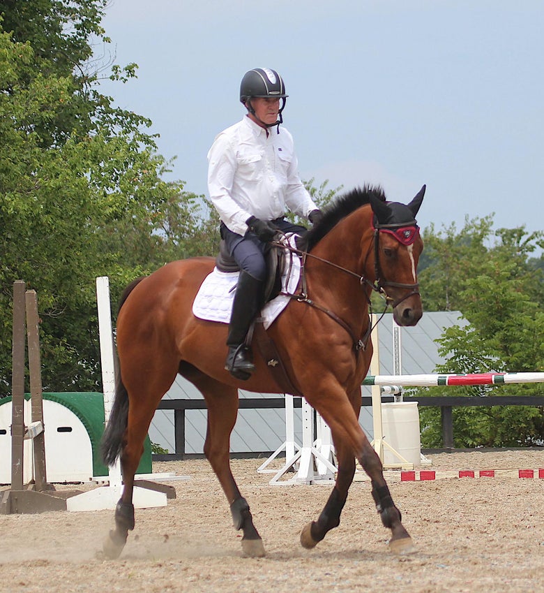 Stephen Bradley riding a bay horse in an arena.