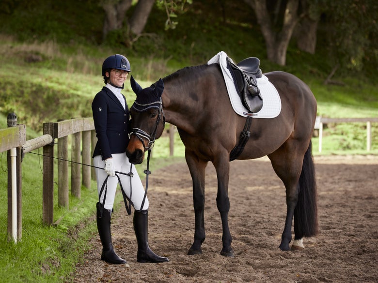 A horseback rider dressed for a dressage show wearing white breeches.