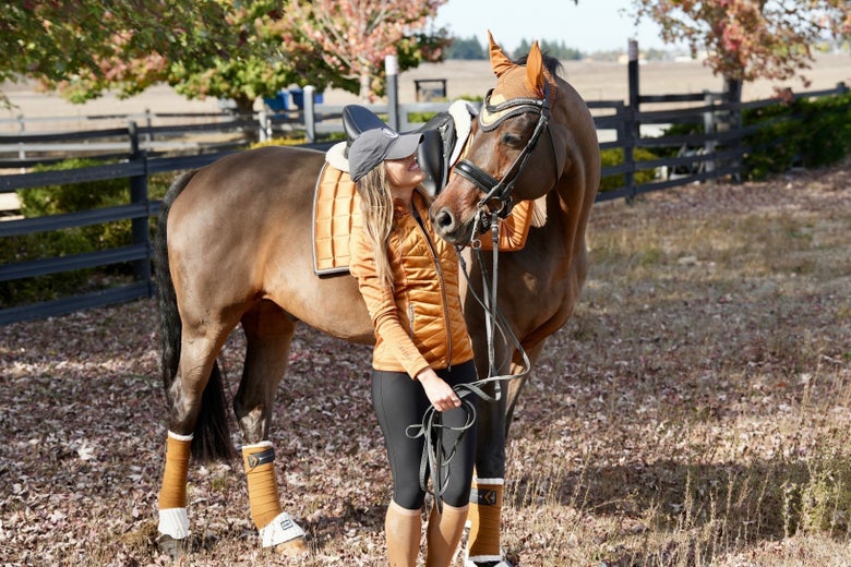 Sponsor Rider Alex Greer petting her bay horse wearing LeMieux fall tack.