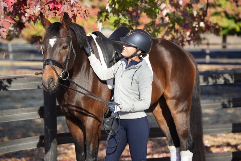 Riding Warehouse Sponsor Rider Alex Greer patting her bay horse.