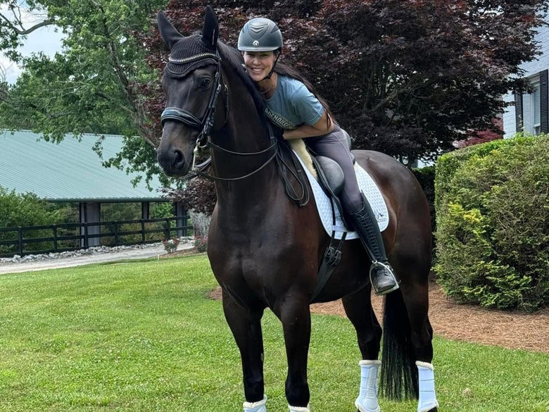 Ashley Marascalco posing for a photo on a dark bay horse.