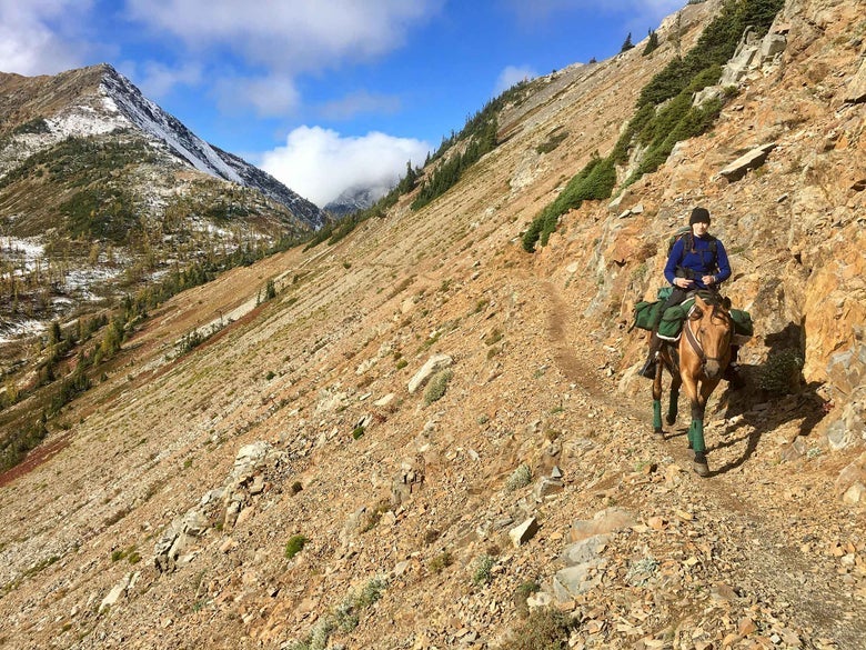 Gillian riding her horse down a cliff face in Washington. 