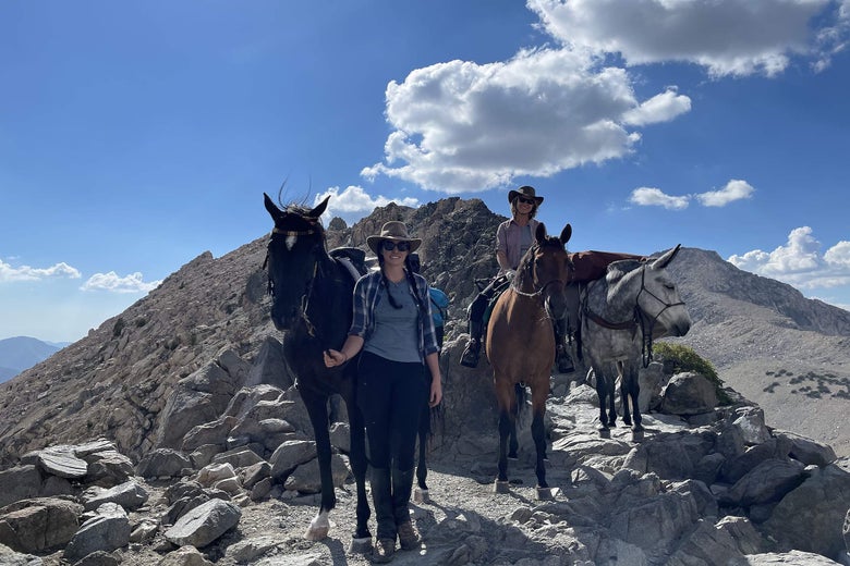 Gillian standing next to her black mare at Glenn Pass, CA. Gillian's mother on horseback, ponying the pack mule. 