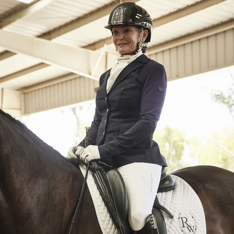 A woman dressed in dressage show attire with a stock tie, riding her black horse.