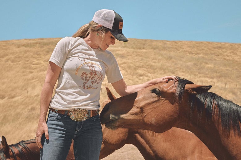 Krista Williams petting a bay horse on the head.