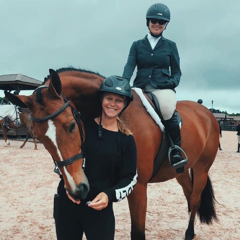 Liz Siadous standing on the ground beside her best friend Katherine Paul on horseback.