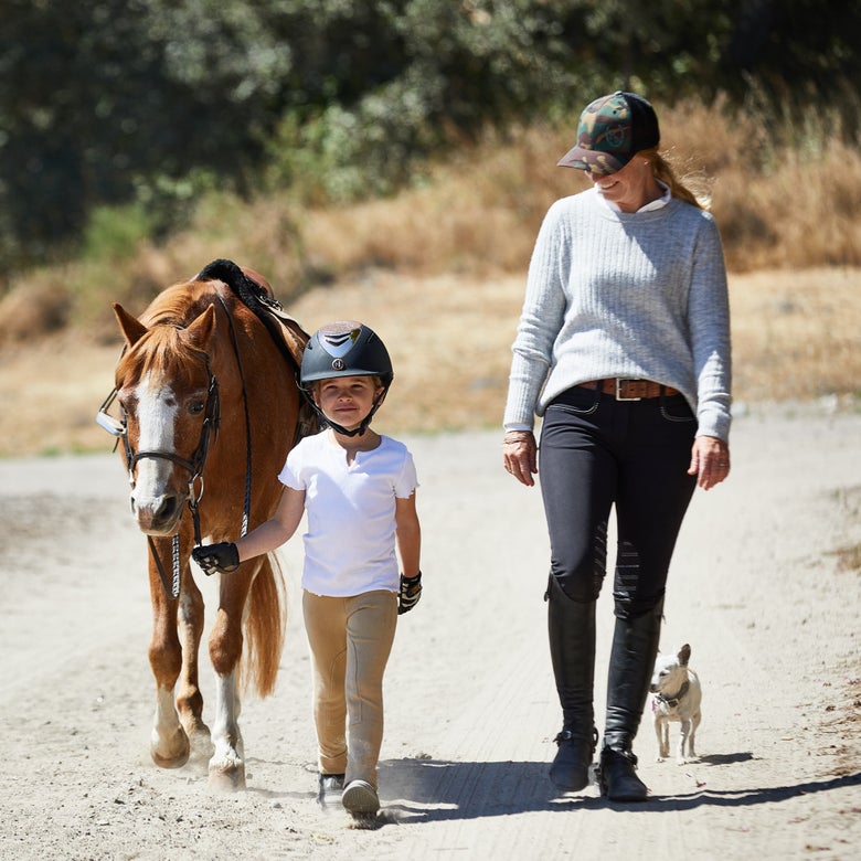 Camp instructor with her riding camp student that is leading a tacked up pony.
