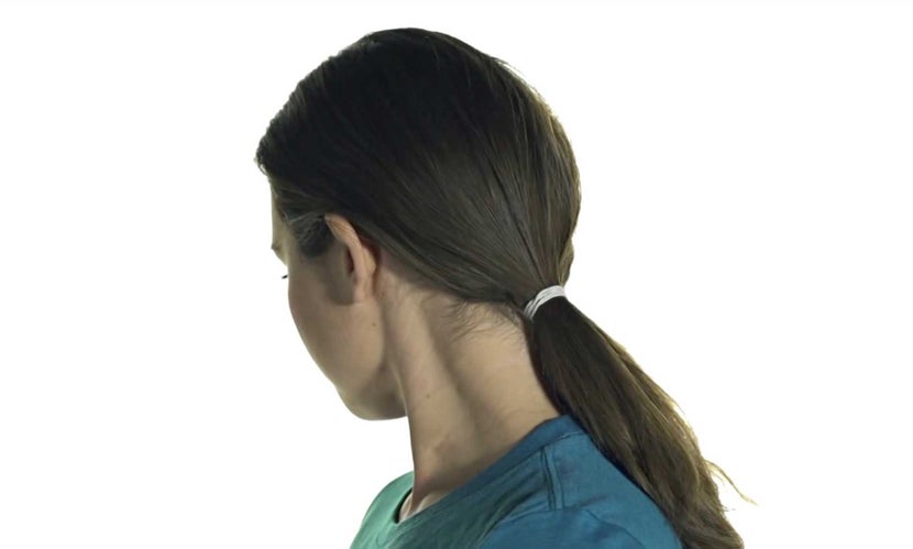 Woman's hair pulled back into a ponytail in prep for putting on a riding helmet. 