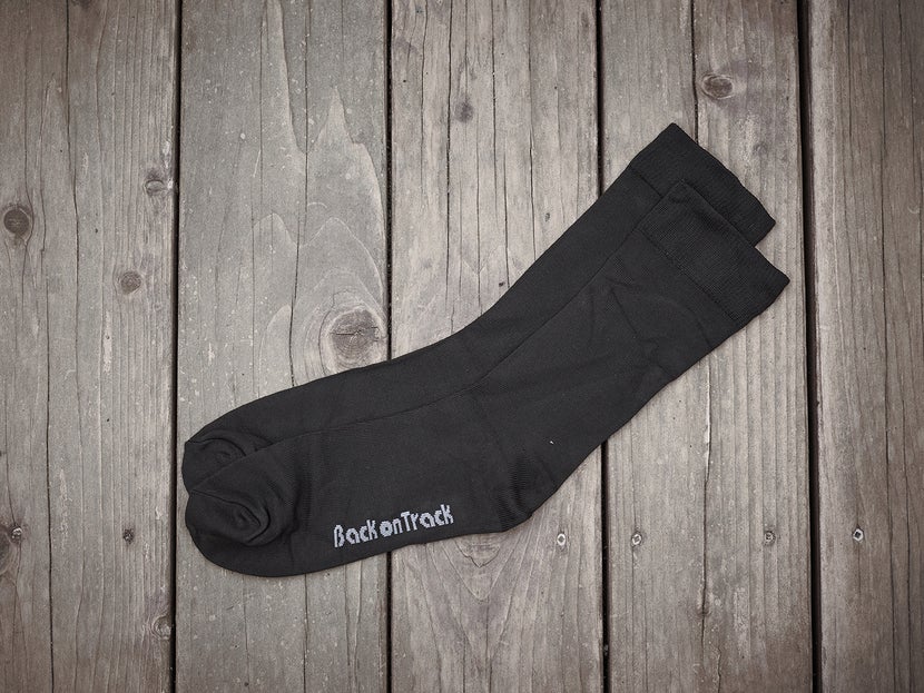 The Back on Track Therapeutic Socks laying flat on a wooden background. 