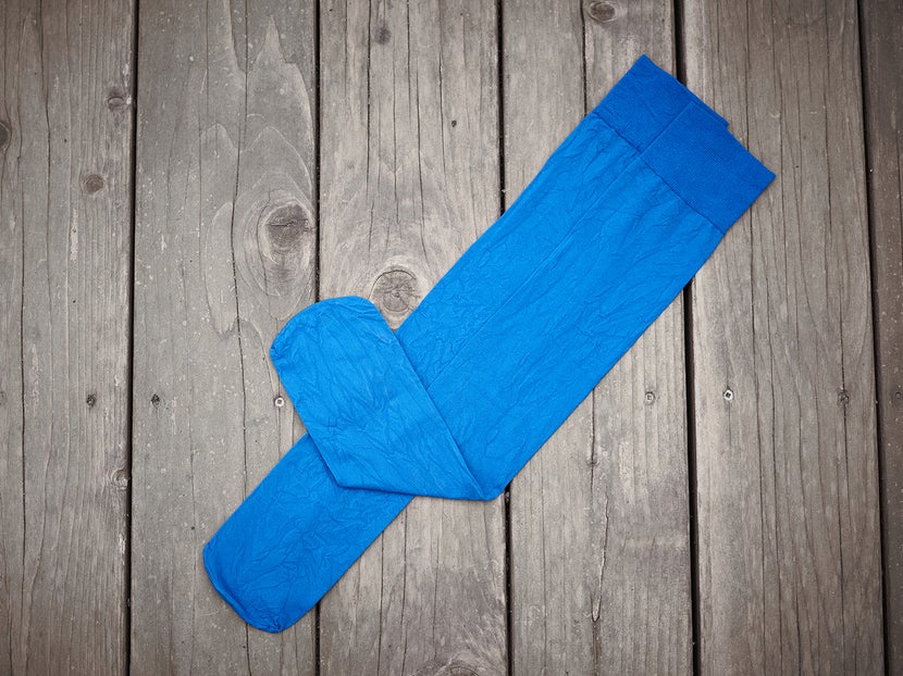 A blue pair of the Ovation Zocks Socks laying flat on a wooden background. 