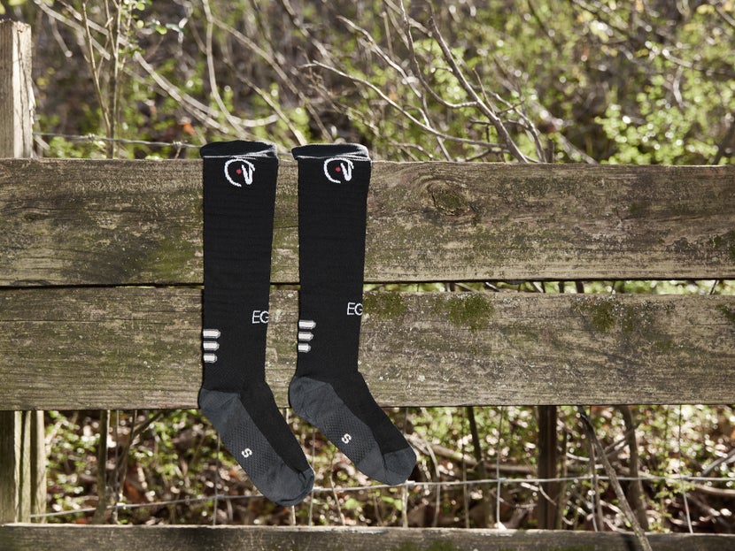 The EGO7 Knee High Tall Boot Air Socks laying over a wooden fence. 