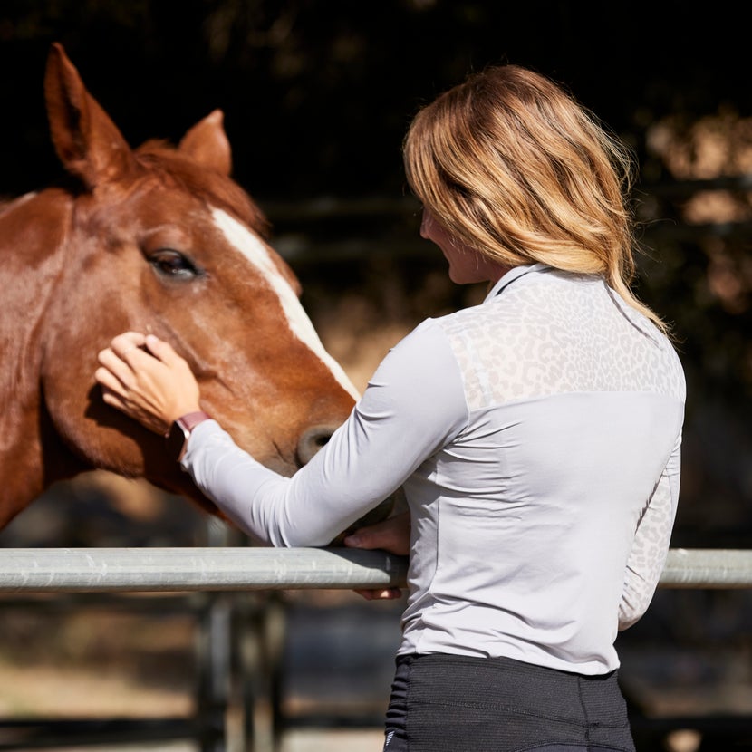 Women petting a chestnut horse, wearing a UV Equestrian Long Sleeve Sun Shirt.