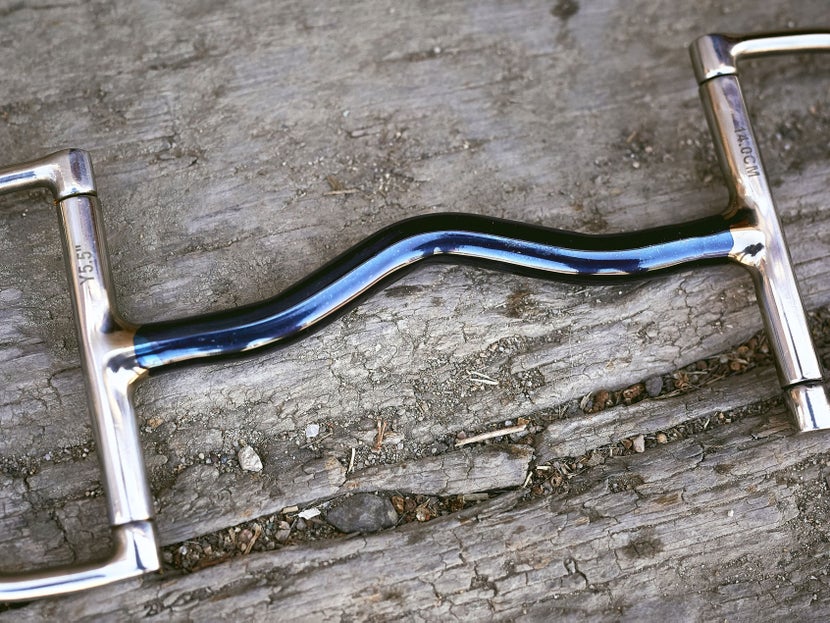 Close up image of a blue alloy bit, laying flat on a piece of wood. 