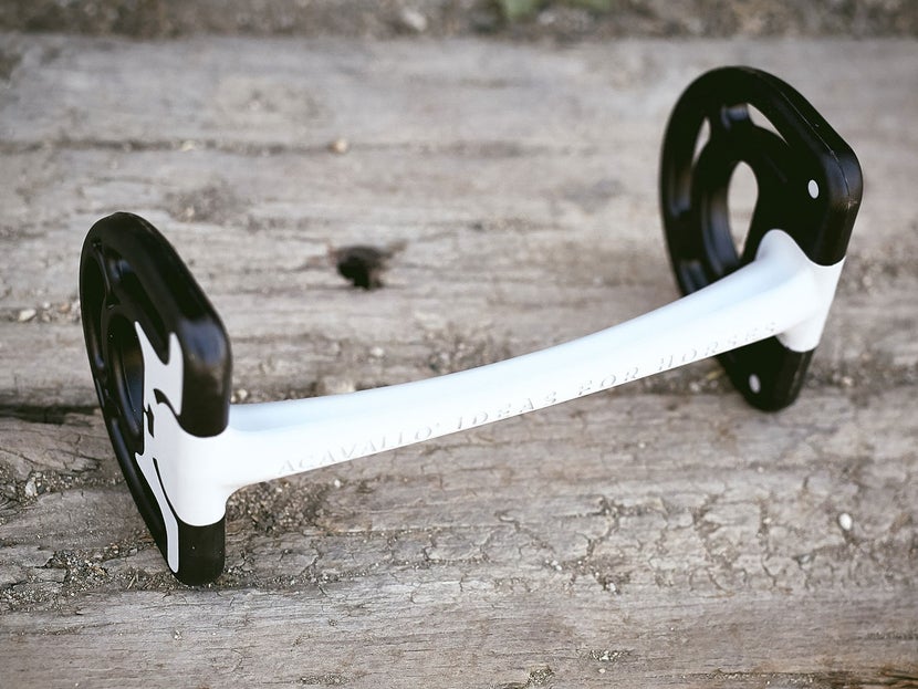 Close up image of a horse bit with a mullen mouthpiece, laying flat on a piece of wood. 
