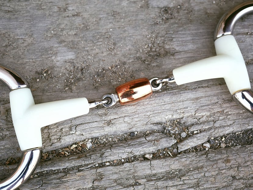 Close up image of a plastic bit with a copper roller, laying flat on a piece of wood. 