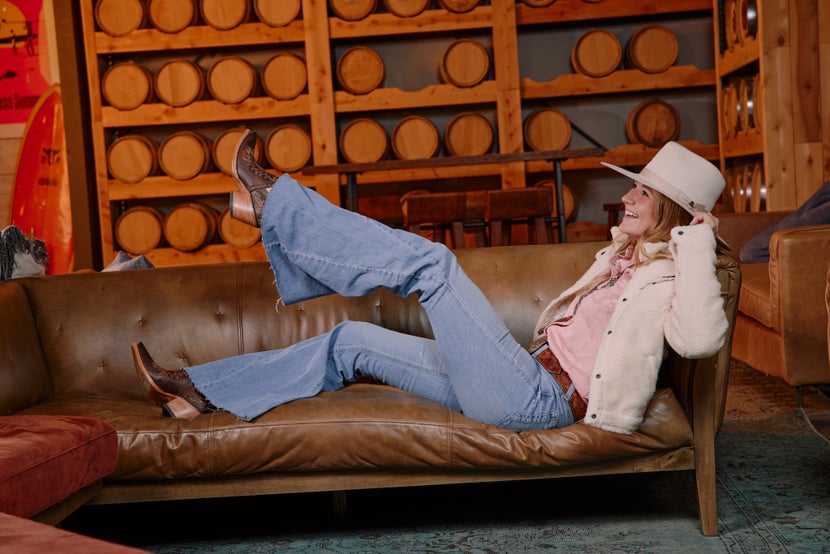 Woman lying on a couch showing off her Ariat cowboy boots.